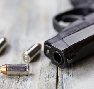a pistol hand gun with bullets on a wooden background